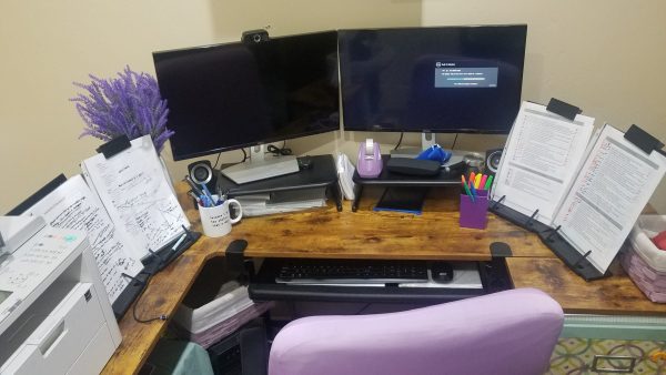 Beacon Point Services – Professional Editing Services Image of a desk with a purple chair, 2 monitors and clipboards with writing on either side of the monitors.